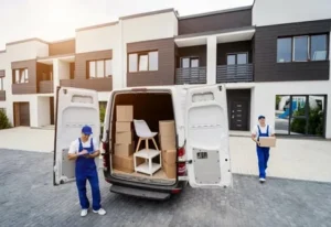 Professional movers unloading boxes from van outside modern residential villa